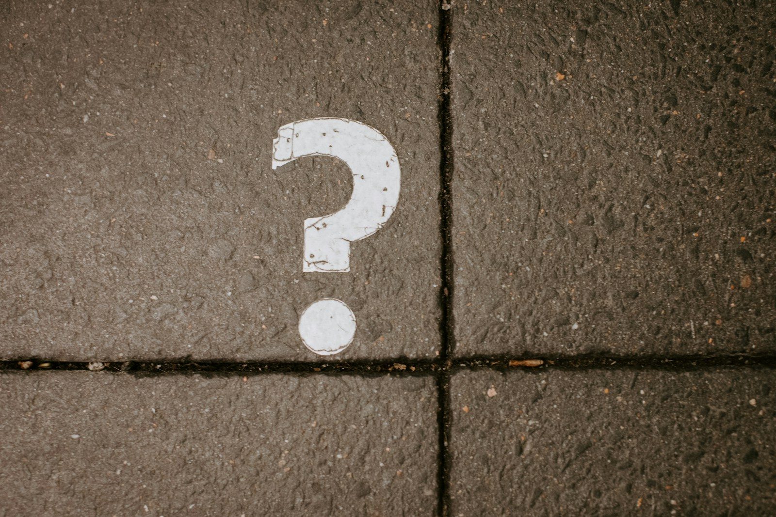 White question mark painted on concrete pavement